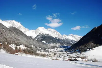 a snowy mountain range with a village in the snow at Hotel Brunnerhof in Rasùn di Sotto