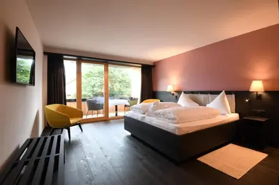 a bedroom with a large bed and a large window at Hotel Brunnerhof in Rasùn di Sotto