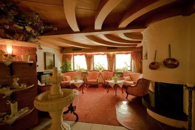 a living room with couches and a table and chairs at Hotel Brunnerhof in Rasùn di Sotto