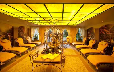 a large living room with couches and a yellow ceiling at Hotel Brunnerhof in Rasùn di Sotto