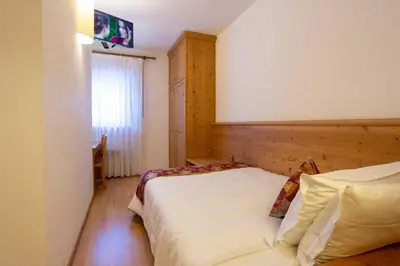 two beds in a hotel room with yellow walls at Hotel San Giusto in Falcade