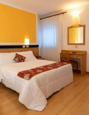 a hotel room with two beds with yellow walls at Hotel San Giusto in Falcade