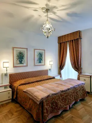 a bedroom with a large bed and a chandelier at Hotel De La Poste in Cortina dʼAmpezzo