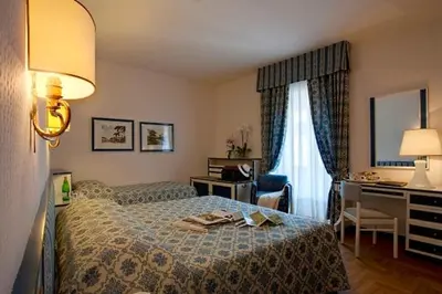 a hotel room with a bed and a desk at Hotel De La Poste in Cortina dʼAmpezzo