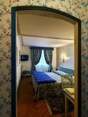 a bedroom with a blue bed and a window at Hotel De La Poste in Cortina dʼAmpezzo