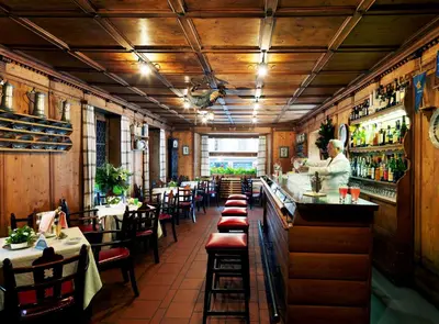 a restaurant with a bar and a chef preparing food at Hotel De La Poste in Cortina dʼAmpezzo