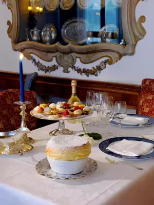 a table with a cake and plates of food on it at Hotel De La Poste in Cortina dʼAmpezzo