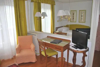 a room with a desk with a television and a bedroom at Hotel De La Poste in Cortina dʼAmpezzo