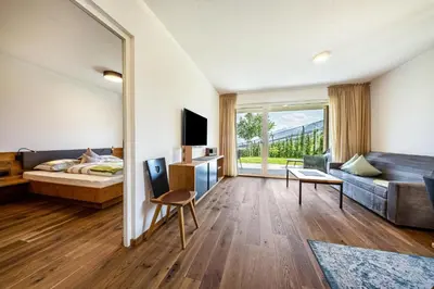 a bedroom with a bed and a living room at Pataunerhof Tirol in Tirolo