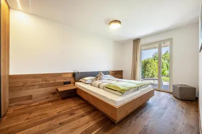 a bedroom with a bed and a large window at Pataunerhof Tirol in Tirolo