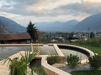 a swimming pool in a yard with mountains in the background at Pataunerhof Tirol in Tirolo