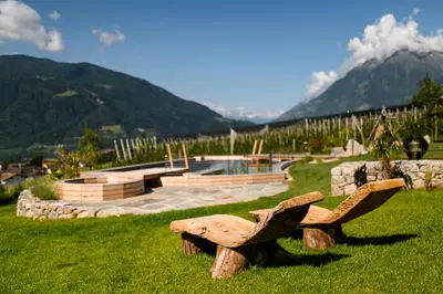 a wooden bench sitting in the grass with mountains in the background at Pataunerhof Tirol in Tirolo