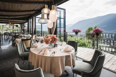 a dining room with a table and chairs with a view at Hotel Lagrein in Schenna