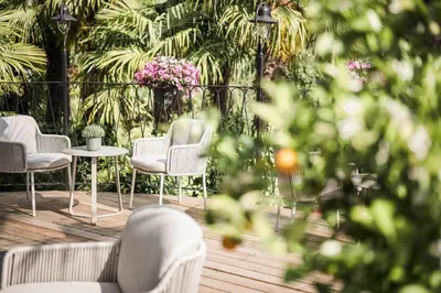 a patio with chairs and a table and flowers at Hotel Lagrein in Schenna