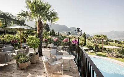 a balcony with chairs and tables and a swimming pool at Hotel Lagrein in Schenna