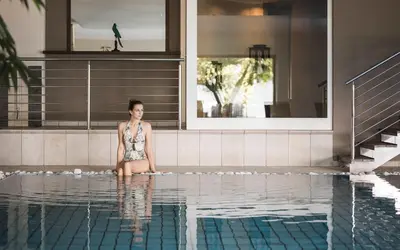 a woman sitting on the edge of a swimming pool at Hotel Lagrein in Schenna