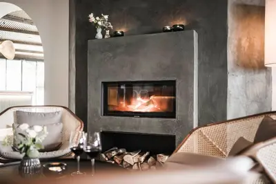 a fireplace in a living room with a table and chairs at Hotel Lagrein in Schenna