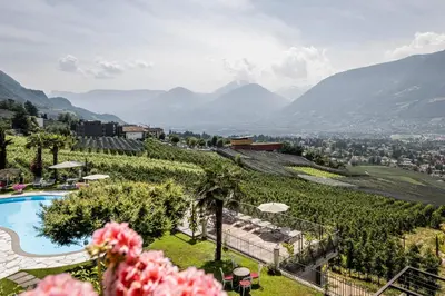 a view of a resort with a pool and mountains at Hotel Lagrein in Schenna