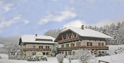 a large building with snow on top of it at Hotel Scherer in Valdaora