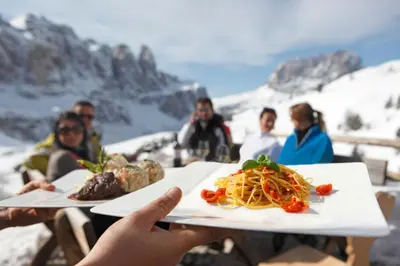 a group of people sitting at a table with a plate of food at Hotel Scherer in Valdaora