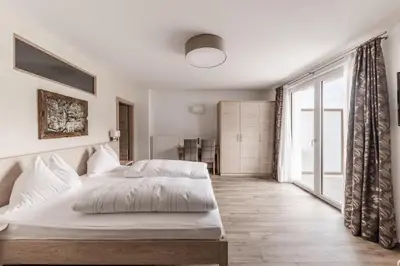 a bedroom with a white bed and a large window at Hotel Oberwirt in Feldthurns
