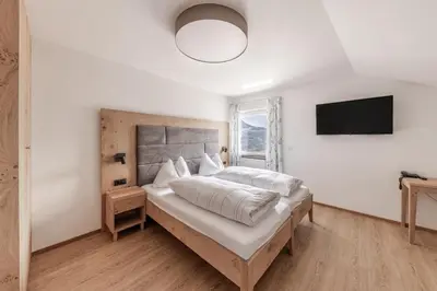 a bedroom with a large bed and a flat screen tv at Hotel Oberwirt in Feldthurns