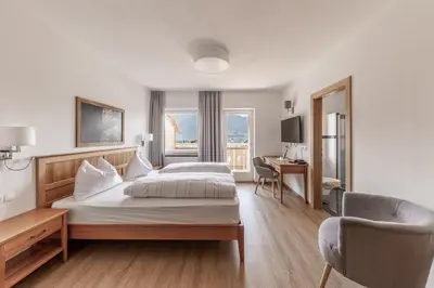 a bedroom with two beds and a desk and a chair at Hotel Oberwirt in Feldthurns