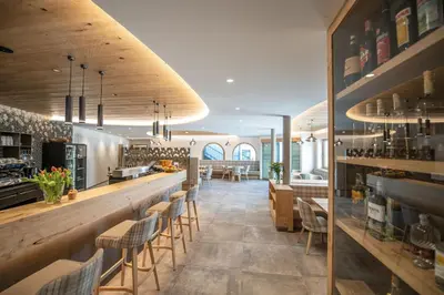 a restaurant with a bar with chairs and tables at Hotel Oberwirt in Feldthurns