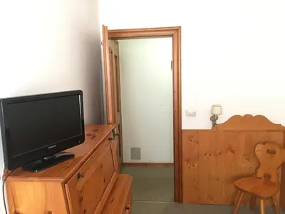 a living room with a tv on a wooden dresser at Hotel Al Larin in Cortina dʼAmpezzo