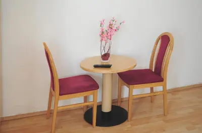 a table with two chairs and a vase with flowers on it at Albergo Casagrande in Laives