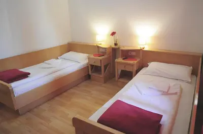 two beds in a small room with two tables at Albergo Casagrande in Laives