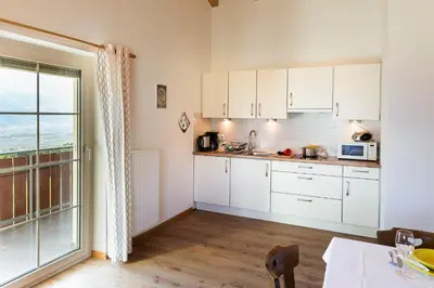 a kitchen with white cabinets and a large window at Mareinhof - Urlaub auf dem Apfelbauernhof in Parcines