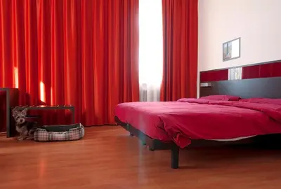 a bedroom with a bed with red drapes at Hotel Fiera in Bolzano