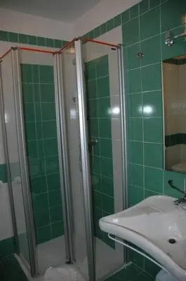 a green tiled bathroom with a sink and a shower at Hotel Fiera in Bolzano