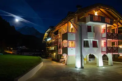 a building at night with the moon in the background at B&B Family Accommodation Canazei SKI-IN SKI-OUT in Canazei