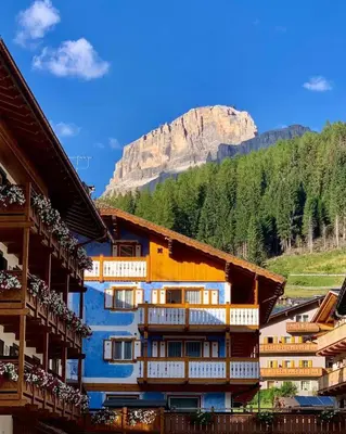 a group of buildings with a mountain in the background at B&B Family Accommodation Canazei SKI-IN SKI-OUT in Canazei