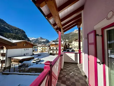 a balcony with pink doors and a view of mountains at B&B Family Accommodation Canazei SKI-IN SKI-OUT in Canazei