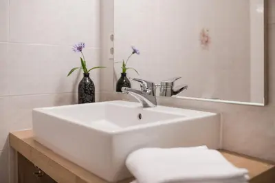 a bathroom with a sink and a vase with purple flowers at Grieserhof Algund in Lagundo