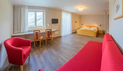 a hotel room with a red couch and a bed at Hotel Untermelz in Plaus