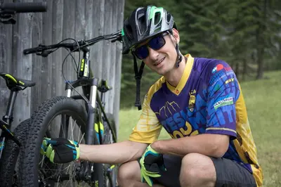 a man wearing a helmet sitting next to a bike at Hotel & Ristorante Baita Dovich in Malga Ciapela