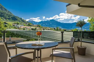 a table and chairs on a balcony with a view of mountains at Das Mitterplarser Hotel in Lagundo