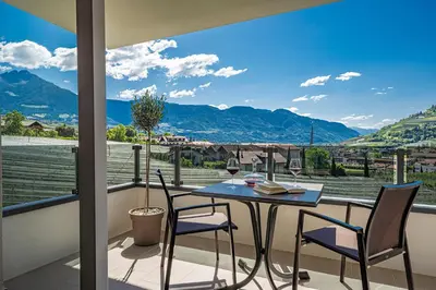 a table and chairs on a balcony with a view of mountains at Das Mitterplarser Hotel in Lagundo