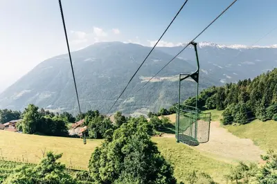 a gondola ride over a field with a mountain at Residence Winklgut in Lagundo