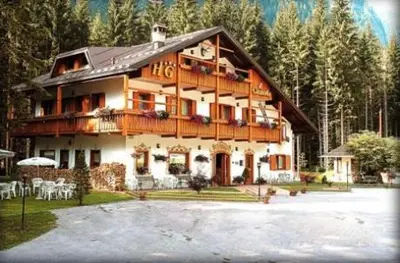 a large wooden house with a lot of tables and chairs at Hotel Garnì Il Cirmolo in Rocca Pietore