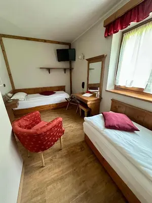 a room with two beds and a chair and a desk at Hotel Garnì Il Cirmolo in Rocca Pietore