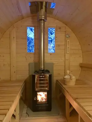 a fireplace in a wooden room with a stove at Hotel Garnì Il Cirmolo in Rocca Pietore