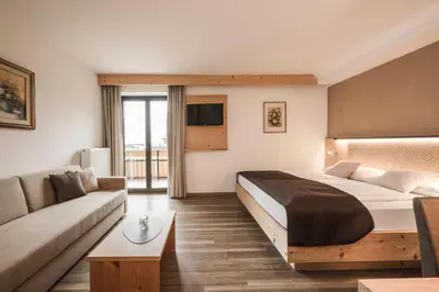 a hotel room with a bed and a couch at Hotel Karin in Tirolo