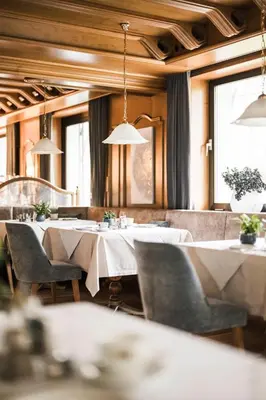 a restaurant with white tables and chairs and windows at Hotel Karin in Tirolo