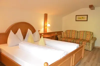 a hotel room with a bed and a chair at Hotel Karin in Tirolo