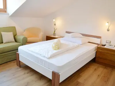 a bedroom with a large white bed and a couch at Hotel Karin in Tirolo